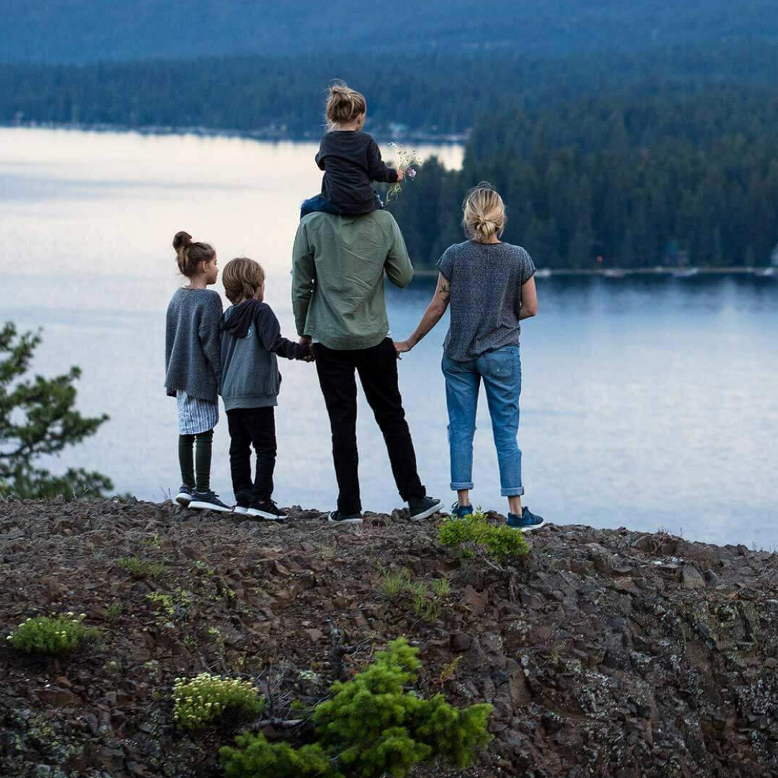 A family stands overlooking a scenic lake with backs to the viewer